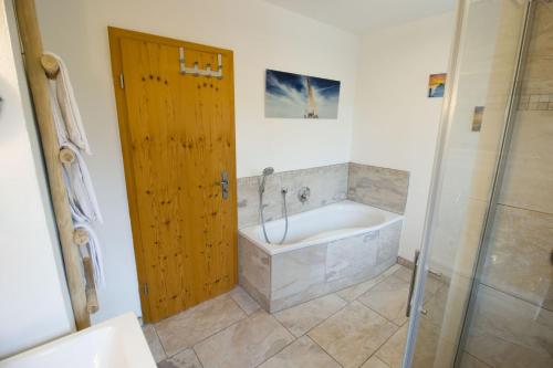 ein Bad mit einer Badewanne, einer Dusche und einer Tür in der Unterkunft Ferienwohnung Lorenz in Heufeld