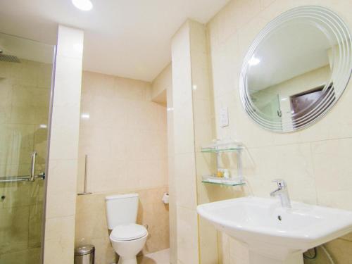 a bathroom with a sink and a toilet and a mirror at BON Hotel Garden City Port Harcourt in Umudara