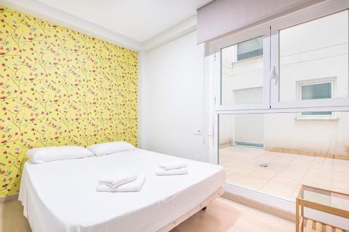 a bedroom with a white bed and a yellow wall at Apartamentos La Rosita Old Town in Benidorm