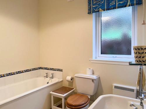 La salle de bains est pourvue d'une baignoire, de toilettes et d'un lavabo. dans l'établissement Grieves Cottage, à Arnisdale