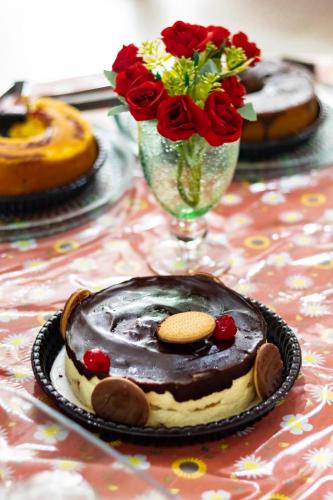a table topped with a chocolate dessert and a vase of flowers at Hotel Pousada Santa Maria in Aparecida