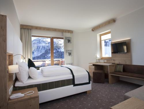 um quarto de hotel com uma cama grande e uma janela em Hotel Nassfeld em Sonnenalpe Nassfeld