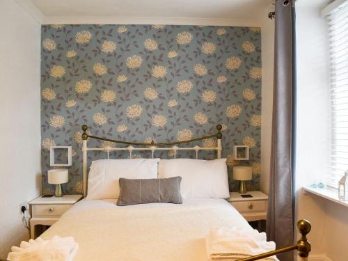 sypialnia z łóżkiem z niebieską i żółtą tapetą w obiekcie Woodville w mieście Porthmadog