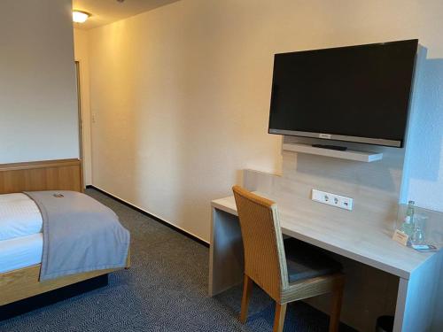 a room with a desk with a tv and a bed at Hotel-Restaurant Goldenstedt in Delmenhorst