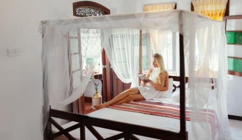 una mujer sentada en una cama leyendo un libro en Grand Villa Hikkaduwa, en Hikkaduwa