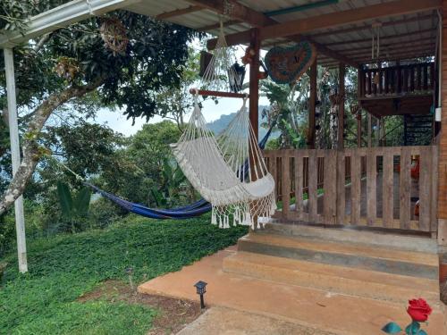 a hammock hanging from the porch of a house at LA CASA DEL BOSQUE Via SALADITO in La Elvira