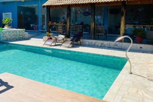 a swimming pool with two chairs next to a house at SÍTIO MARAVILHOSO EM MAIRIPORÃ opção de 1 quarto para 8 pessoas ou 4 quartos acima de 9 pessoas in Mairiporã