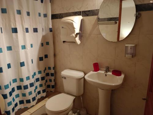 a bathroom with a toilet and a sink and a mirror at cabañas Te Pito Kura in Hanga Roa