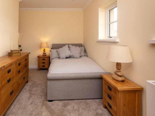 a bedroom with a bed and a dresser and a window at The Cottage At Briarlea in Larkhall