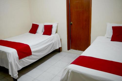 two beds with red and white sheets in a room at Hotel Rosa del Alba, Malecón Chetumal in Chetumal