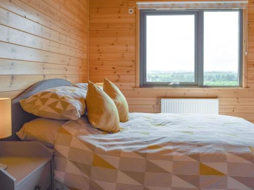 a bed in a wooden room with two windows at The Lodge in Great Easton