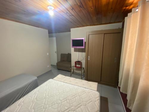 a bedroom with a bed and a tv in a room at Apartamento aconchegante próximo Capivari in Campos do Jordão