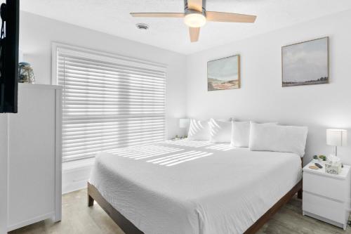 a white bedroom with a bed and a ceiling fan at Willapye Beach House by the Sea in Navarre