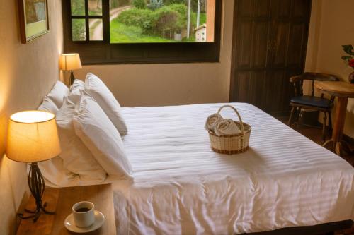 a white bed with a basket on top of it at Hotel Termales El Batan in Cuítiva