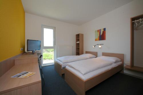 a bedroom with two beds and a tv and a window at Tour-Motel in Wilfersdorf