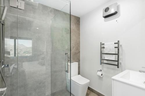 a bathroom with a shower and a toilet and a sink at A Luckie Charm - 5-Bedroom Townhouse with Spectacular View in Queenstown