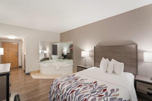 um quarto de hotel com uma cama e uma banheira em Red Roof Inn & Suites Carrollton, GA - West Georgia em Carrollton