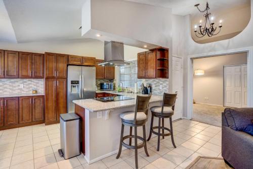 a kitchen with wooden cabinets and a island with bar stools at 7 Mi to Dtwn Chandler Pet-Friendly Condo with Pool in Chandler