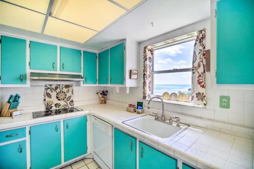 une cuisine avec des placards bleus, une fenêtre et un évier dans l'établissement Spacious Satellite Beach Condo with Balcony!, à Satellite Beach