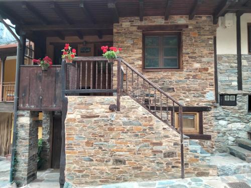 a stone house with a staircase and flowers on it at VUT El Pajariel Ponferrada in Ponferrada