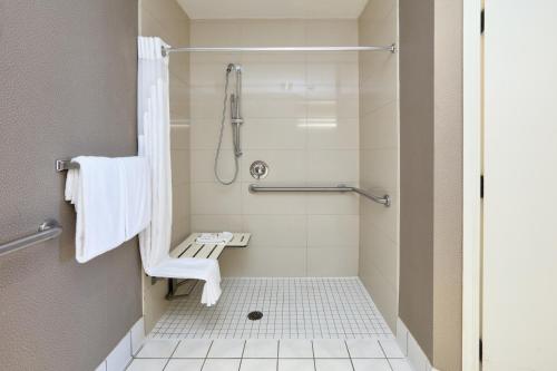 a bathroom with a shower with a chair in it at Homewood Suites by Hilton Santa Maria in Santa Maria