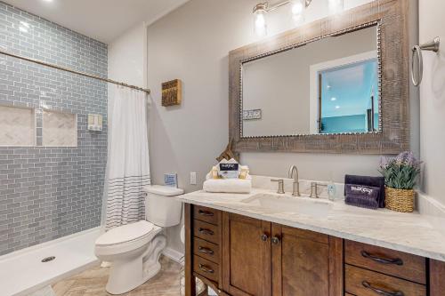 uma casa de banho com um lavatório, um WC e um espelho. em Coastal Haven - Unit C - Downstairs em Kill Devil Hills