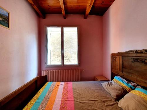 Schlafzimmer mit einem Bett und einem Fenster in der Unterkunft Appartement au calme au cœur du village in Saint-Beauzély