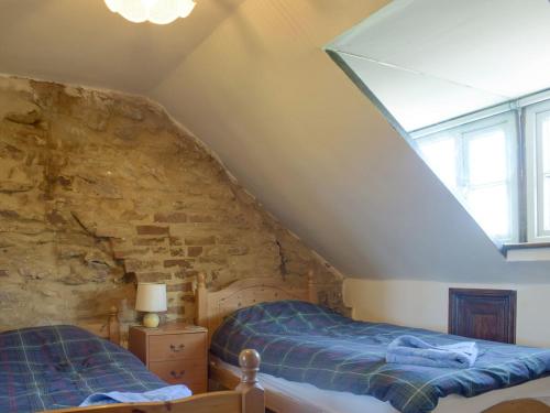 a attic bedroom with two beds and a stone wall at Doward Farm in Symonds Yat