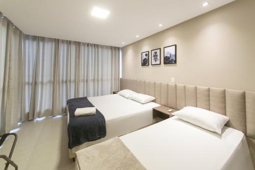 a hotel room with two beds and a window at Casa Requinte Com piscina 02 in Balneário Camboriú