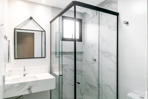 a bathroom with a shower and a sink and a mirror at Casa Requinte Com piscina 02 in Balneário Camboriú