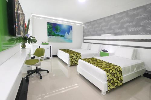 a hotel room with two beds and a desk at Hotel Genova Prado in Barranquilla