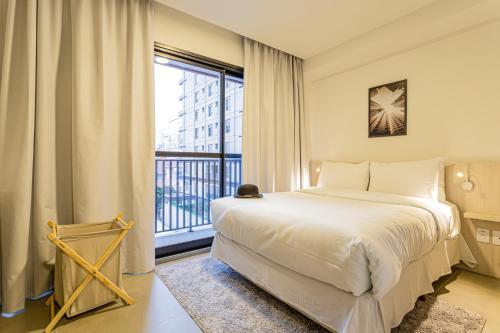 um quarto com uma cama e uma grande janela em Charlie Sabiá Moema em São Paulo