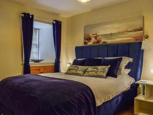a bedroom with a blue bed with two pillows at Ardvar in Crail