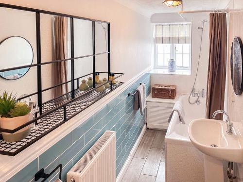 y baño con bañera, lavabo y espejo. en Tubs Cottage en Kingsteignton
