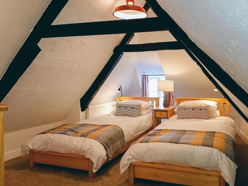 two beds in a room with a roof at Tubs Cottage in Kingsteignton