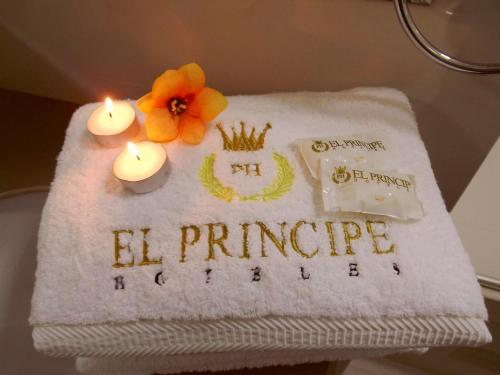 a white towel with candles and a flower on it at El Principe Hoteles in Piura