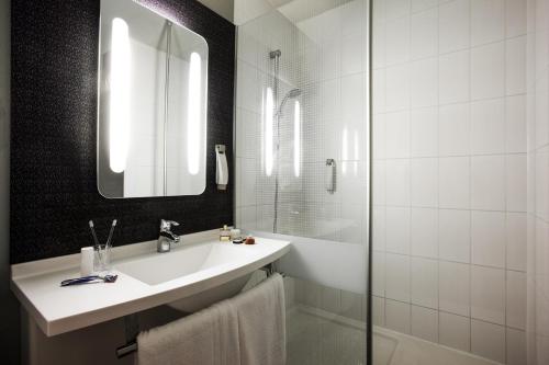 Baño blanco con lavabo y espejo en ibis Pau Lescar en Lescar
