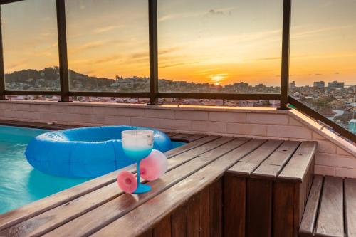 アハイアウ・ド・カボにあるCobertura Pé na Areia- Piscina, Churrasqueira, Vista Mar e a 50m da Praia dos Anjosのスイミングプールの横のテーブルでのドリンク