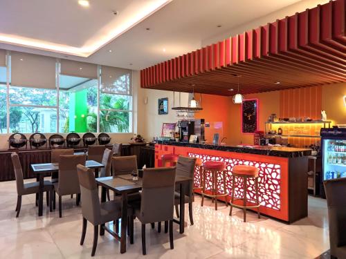 a restaurant with tables and chairs and a bar at Front One Hotel Purwodadi in Purwodadi