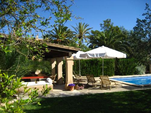 un patio con sillas y una sombrilla junto a la piscina en Finca Raims en Algaida