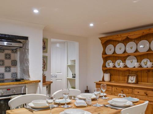 una cocina con una mesa con sillas y platos. en Cobblers Cottage en Petworth