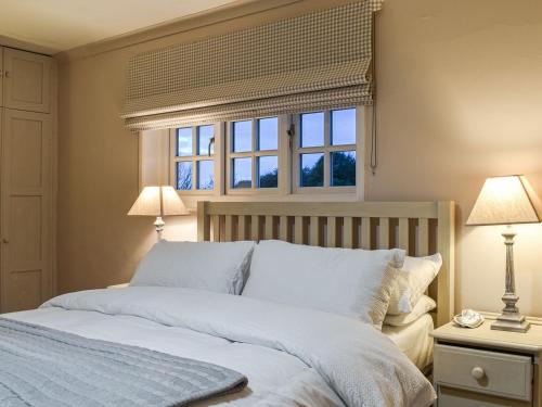 a bedroom with a bed with two lamps and a window at Cobblers Cottage in Petworth