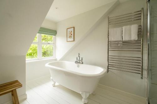 een witte badkamer met een bad en een raam bij Pinewood - Aldeburgh Coastal Cottages in Aldeburgh