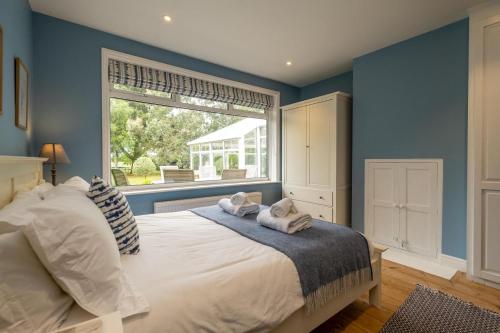 a bedroom with blue walls and a bed with towels on it at Pinewood - Aldeburgh Coastal Cottages in Aldeburgh