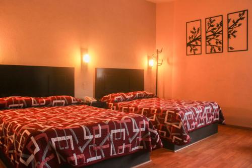 サカテカスにあるHotel Alikaのオレンジ色の壁のホテルルーム内のベッド2台