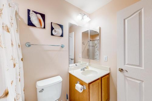a bathroom with a sink and a toilet and a mirror at Millville by the Sea --- 23772 Pembroke Lane in Millville