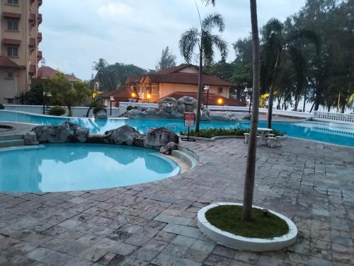 - une piscine dans un complexe avec un palmier dans l'établissement Pantai Puteri Kondominium, à Kampong Bukit Darat