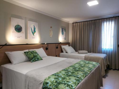 um quarto de hotel com duas camas e uma janela em B14 Suítes em Penha