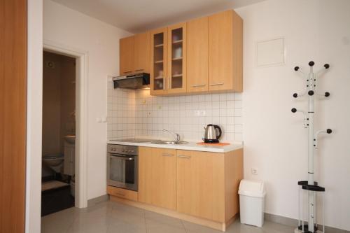 uma pequena cozinha com armários de madeira e um lavatório em Studio Icici 7785a em Ičići