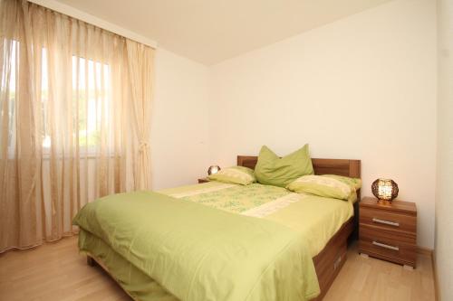 a bedroom with a bed with green sheets and a window at Apartments with a parking space Icici, Opatija - 7785 in Ičići